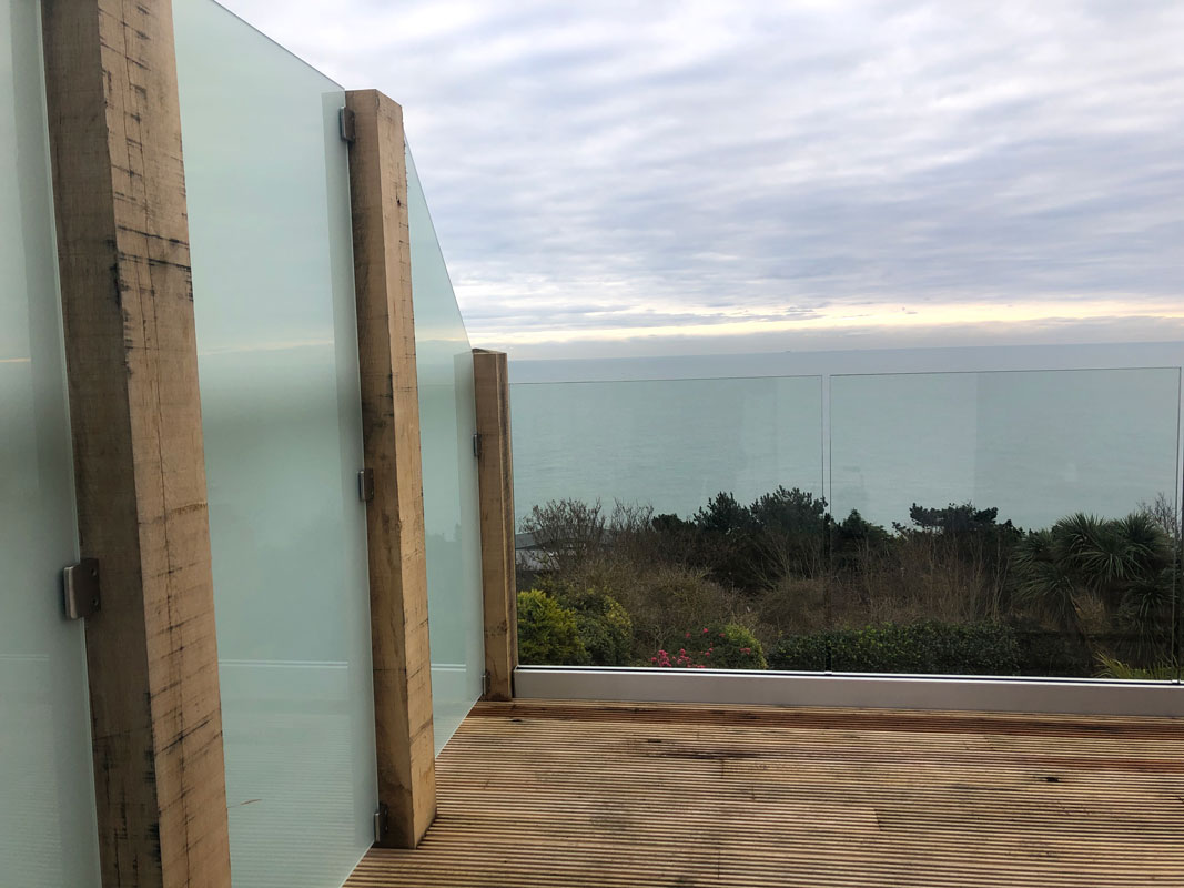 Frameless glass balustrade around a decked terrace looking out to sea